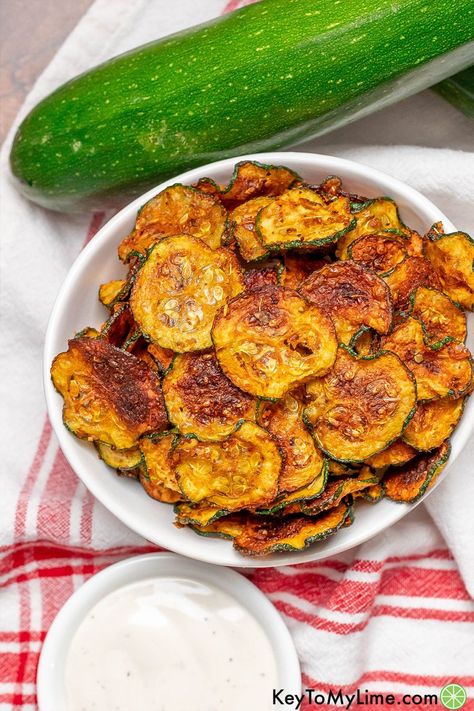 These crispy zucchini chips can be baked in the oven or air fried. They’re the perfect summer snack and have a delicious flavor. This is the best way to get your entire family to enjoy eating zucchini! KeyToMyLime.com Zucchini Chips Oven, Crispy Zucchini Chips, Zucchini Fries Baked, Zucchini In The Oven, Crispy Zucchini, Zucchini Chips Recipe, Kale Chip Recipes, Zucchini Bites, Zucchini Chips Baked