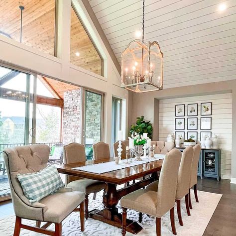 This modern farmhouse-styled dining space features a long wooden table matched with cushioned grey chairs. A rustic chandelier hangs from the striped white cathedral ceiling. The table is accessorized with an elegant table runner and mismatching candles. White Cathedral Ceiling, Cathedral Ceiling Ideas, White Cathedral, Brick Fireplace Wall, Elegant Table Runner, White Kitchen Cupboards, Airy Home, All White Bedroom, Natural Stone Fireplaces