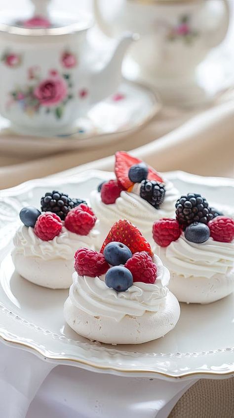 Meringue pavlova mini cakes adorned with fruit and cream on a pristine white plate, with a coffee pot in the background royalty free stock photos Wildflower Desserts, Pavlova Station, Pavlova Cups, Pavlova Mini, Australian Party, Fruit And Cream, Mini Pavlovas, Pavlova Dessert, Mini Meringues