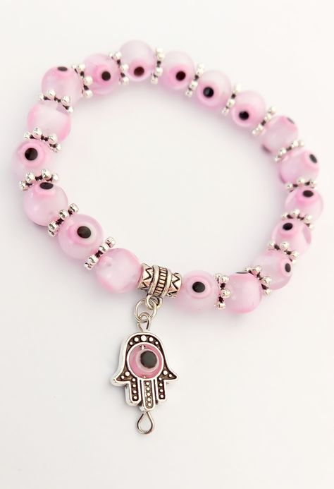 The Pink Evil Eye Charm Bracelet is a beautiful and unique piece of jewelry that combines the protective symbolism of the Evil Eye with the feminine charm of the color pink. The bracelet features a delicate chain adorned with a small Evil Eye charm in shades of pink and white.

The Evil Eye is a powerful talisman that is believed to protect against negative energy and ward off the envy of others. The pink color of the charm adds a touch of femininity and elegance to the bracelet Pink Beaded Bracelet With Evil Eye, Pink Evil Eye Bracelets, Cheap Pink Evil Eye Bracelets, Evil Eye Pink Bracelet, Pink Spiritual Evil Eye Jewelry, Pink Evil Eye, Eye Meaning, Pink Eye, High Vibrational