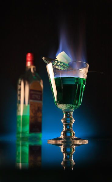 The Bohemian Method of absinthe ritual involves fire, and was not performed in the Belle Époque. Like the French method, a sugar cube is placed on a slotted spoon over a glass containing one shot of absinthe. The sugar is pre-soaked in alcohol (usually more absinthe), then set ablaze. The flaming sugar cube is then dropped into the glass, thus igniting the absinthe. Finally, a shot glass of water is added to douse the flames. This method tends to produce a stronger drink than the French method. Green Fairy Cocktail, Flaming Cocktails, Flaming Drinks, Green Fairy Absinthe, Strong Drinks, Slotted Spoon, Green Fairy, The Bohemian, Absinthe