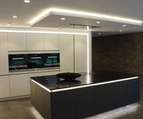 A monochromatic modern kitchen with lighting around the perimeter in addition to the small pot lights in the ceiling. To the right is a stacked stone wall. Kitchen Lighting Ideas For Low Ceilings, Contemporary Kitchen Island Lighting, Kitchen Ceiling Design, Blitz Design, Drop Ceiling Lighting, Drop Ceiling, Kitchen Lighting Ideas, Bright Kitchens, Kitchen Ceiling Lights