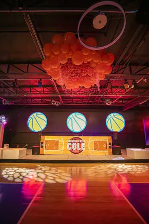 A basketball themed Bar Mitzvah transformed this venue with a court-inspired dance floor, suspended basketball balloon fixture hanging from the ceiling, and more. Come see more details from the party to get more sports-themed Mitzvah ideas and inspiration. Basketball Bar Mitzvah, Basketball Theme Party, Edible Favors, Basketball Theme, Indoor Event, Sports Themed Party, Teen Love, March Madness, Theme Ideas