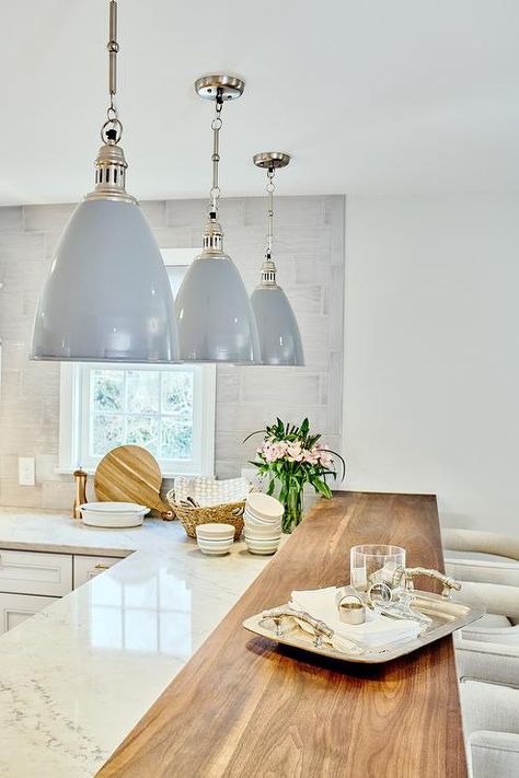 Wood top breakfast bar extended from a white quartzite l-shaped countertop under a set of gray industrial lights. Island Decor Kitchen, Calcutta Marble Kitchen, Calcutta Gold, Industrial Lights, White Quartzite, Breakfast Bar Lighting, Kitchen Peninsula, 2024 Kitchen, Kitchen Island Decor