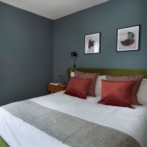 This mid-century style bedroom was created for a young couple with a small budget. The room is naturally dark so we embraced the low light and used a blue / grey paint from Lick to cocoon the room, creating a cosy, luxurious feel. Room designed by modern, sustainable interior design studio Felicity White Interiors. Accents of rust red, brown and olive green add to the luxury, nostalgic feel. Olive Green And Red Bedroom, Green And Red Bedroom, Grey Green Bedrooms, Mid Century Style Bedroom, Blue Grey Paint, Bedroom Colours, Sustainable Interior, Sustainable Interior Design, Mid Century Bedroom