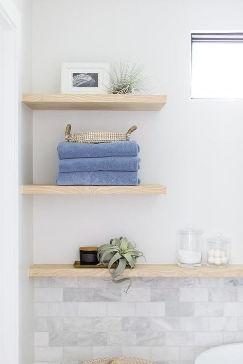 Cottage bathroom with an oak wooden floating wall shelves above marble subway tiles styled with bathroom decor, towels, and bath accessories. Shelves Above Bathtub, Bathroom Floating Shelves, Wooden Bathroom Shelves, Bathroom Decor Towels, Oak Floating Shelves, Marble Subway Tiles, Vintage Tub, White Shiplap Wall, Floating Shelves Bathroom