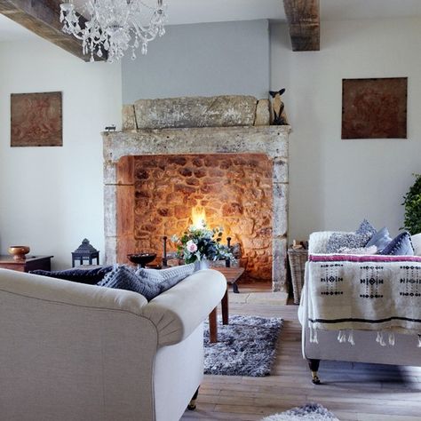 A colour palette of blues, greys and limed wood contrasts with the exposed beams and stone fireplace in this living room decorating idea. A large open fire creates a stunning focal point. Design Camino, Winter Living Room, Farmhouse Fireplace, Country Living Room, Pool Design, French Farmhouse, French Country House, Fireplace Mantle, Fireplace Design