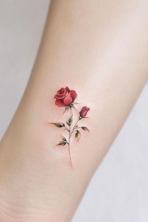 A small, delicate tattoo of a red rose with green leaves on a person's skin. Tiny Rose Tattoos For Women, Small Roses Tattoo, Rose Tats, Rose Stem Tattoo, Meaningful Small Tattoos, Rose Tattoo Behind Ear, Small Compass Tattoo, Small Mountain Tattoo, Rose Tat