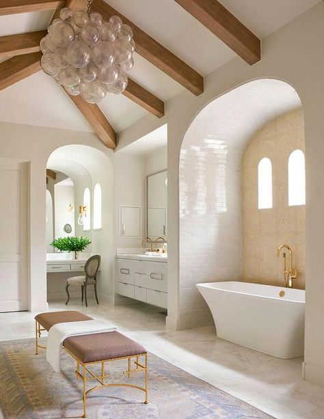 Sophisticated master bathroom features a vaulted ceiling dotted with wood beams as well as a smoke gray glass bubbles chandelier, Oly Studio Muriel Chandelier, illuminating a gold leaf bench upholstered in gray linen fabric placed atop a gray and blue rug. Bad Inspiration, Small Bathroom Design, Dream Bathrooms, Style At Home, Beautiful Bathrooms, House Inspo, Dream Home Design, Bathroom Inspiration, 인테리어 디자인