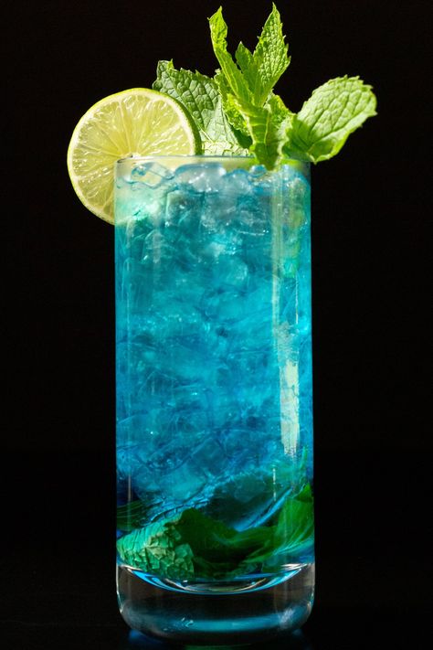 This tropical twist on the classic mojito cocktail uses blue Curacao to get its vibrant color. Mint, lime, and citrus flavors pared with rum. Gsm Blue Mojito, Classic Mojito, Mango Mojito, Iced Drinks Recipes, Mint Mojito, Blue Drinks, Mojito Cocktail, Colorful Cocktails, Mojito Recipe