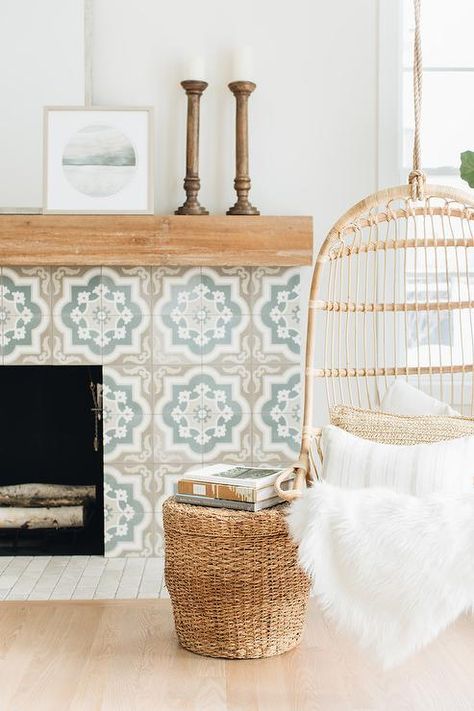 A tan and blue Moroccan style tiled fireplace boasts a rustic wood mantel and is positioned behind a Serena & Lily Hanging Rattan Chair paired with a woven ottoman. Hanging Rattan Chair, Hanging Rattan, Deco Nature, Wood Mantels, Fireplace Ideas, Style Deco, Cabin Life, Fireplace Tile, Rattan Chair