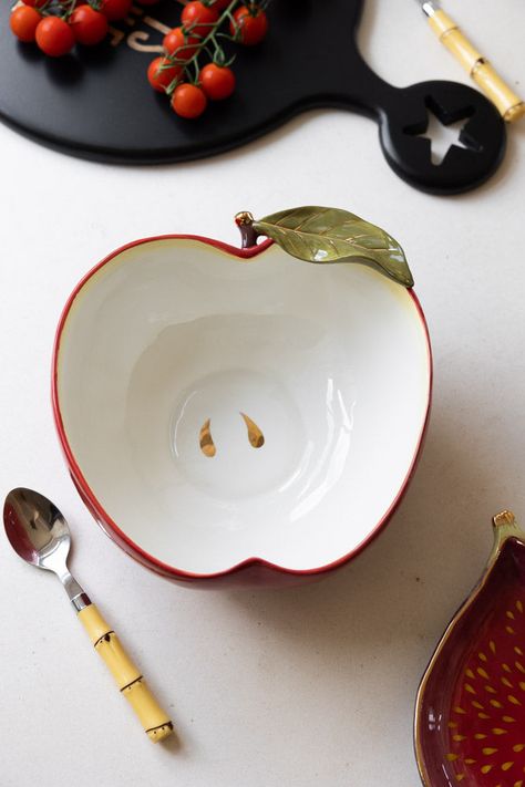 If you’re a fan of Italiana ceramic kitchen chic, you’ll love this beautiful apple-shaped serving bowl. It's a deep, roomy piece, and is exquisitely crafted, painted in a glorious deep red and apple white (of course). Particular care has been taken over the stem and leaf detailing, which are picked out in verdant green and glossy gold for an extra splash of sass. The golden pips at the bottom of the bowl are a lovely touch, too. Whether you indulge in a little family time, and use this for indul Fruit Ceramic Bowls, Ceramics Bowl Ideas, Apple Pottery, Apple Ceramic, Ceramic Apple, Verdant Green, Unique Plates, Pot Ceramic, Leaf Bowls