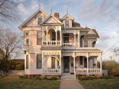 This detailed exterior is an authentic example of the gingerbread-style Victorian. Delicate architectural detail and a multi-gabled roofline are characteristic of the style and era. White molding decorates the front porch and multiple balconies, providing subtle contrast to the pale pink exterior for added visual interest. Victorian Home Exterior, Victorian Homes Exterior, Old Victorian House, Victorian Style House, Pink Victorian, Victorian Style Homes, Casas The Sims 4, Victorian Mansions, Victorian Architecture