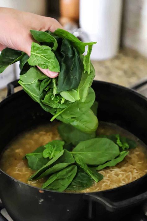 A person dropping fresh spinach into a black pot filled with chicken broth and ramen noodles. Spinach Ramen Noodle Recipes, Ramen With Poached Egg, Spinach Ramen, Ramen Recipes Easy, Easy Ramen, Top Ramen, Ramen Noodle Soup, Ramen Noodle Recipes, Spinach Egg