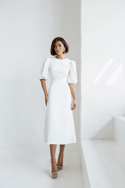 Embrace pure elegance with our White Puff Sleeve Midi Dress. The pristine white hue exudes sophistication and charm, making it a versatile choice for various occasions. The puff sleeves add a touch of drama and femininity to the classic midi length, ensuring you'll look effortlessly chic and stylish. #whitedress #puffsleeve #dress #dresses #mididress #stylish #elegant #eveningwear #eveningdress #partydress #promdress #dresslover #weddingdress #fashion White A Line Midi Dress, Casual Winter Wedding Dress Simple, White Puff Sleeve Midi Dress, White Dresses Midi, Off White Dresses Classy, White Graduation Dress Midi, Elegant Midi Dresses Classy Chic, White Midi Dress Classy, Simple White Dress Classy