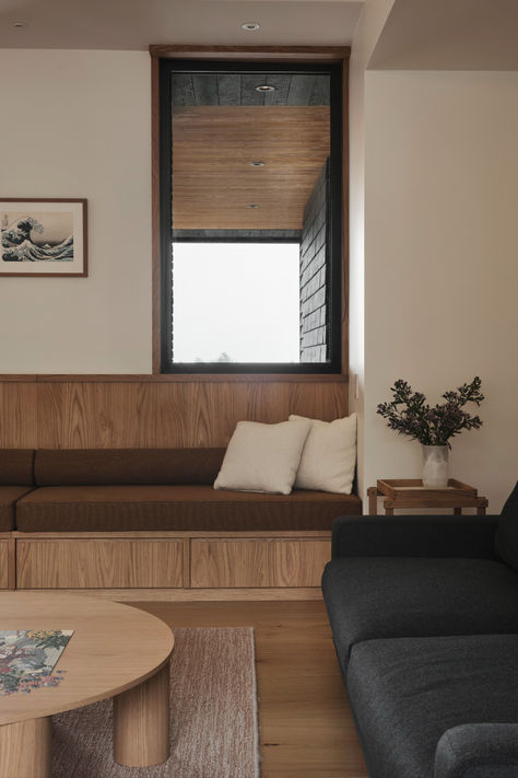 Modern living room featuring minimalist wood decor, brown built-in bench seating, and a serene design aesthetic. Bench Nook In Living Room, Floating Bench Living Room, Black Cedar House, Window Bench Seating, Mcm Bench, Library Bench, Modern Window Seat, Oak Window Sill, Bay Window Benches