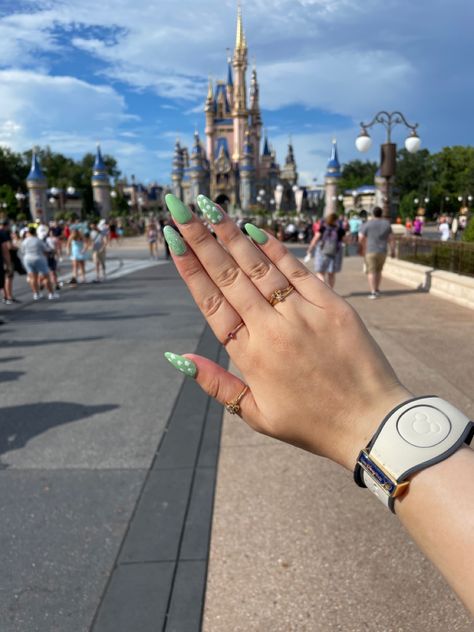 sage green almond shaped acrylic nails, with white mickey heads on the thumb and ring finger, and silver glitter on the index finger, with Cinderella Castle in the background Green Nails With Glitter, Sage Green Nails, Disney Acrylic Nails, Disney Nail, Green Acrylic Nails, Nails With Glitter, Disney Nails, Mickey Head, Green Nails