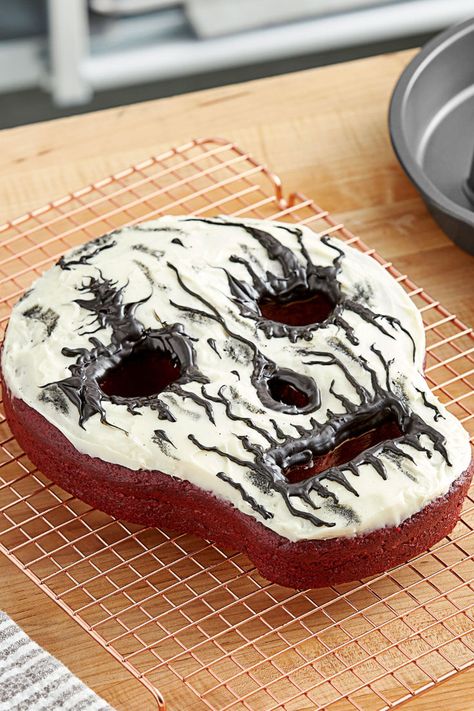 A halloween cake in the shape of a skull next to a skull shaped baking pan. Skull Cake Pan, Baking Fall, Restaurant Aprons, Wilton Cake Pans, Skull Shape, Skull Cake, Bake Cakes, Measuring Cups And Spoons, Festive Desserts