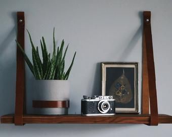 Leather strap shelves are a simple, easy and cheap way to change your interior. They will add a unique character and make the shelves a unique decorative element in your home. You can do it yourself! Leather Strap Shelf, Leather Shelf, Shelves Plant, Leather Strap Shelves, Pallet Wall Shelves, Leather Kitchen, Floating Shelf Brackets, Wooden Floating Shelves, Nursery Shelves