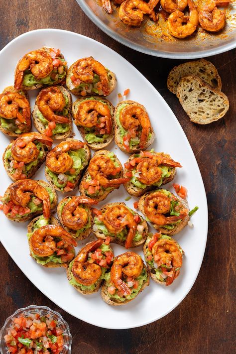 These Shrimp Crostini bites are an easy crowd pleasing appetizer that comes together in less than 30 minutes. Toasted baguette is topped with guacamole, fresh salsa, and spicy cajun shrimp. These make delicious party finger food or a fun and fancy movie night snack all year round! Shrimp Finger Food Party Appetizers, Bday Party Snacks Finger Foods, Dinner Party Finger Food Ideas, Shrimp Finger Food, Shrimp Crostini Appetizers, Cute Finger Foods, Cocktail Party Food Appetizers, Easy Fancy Appetizers, Fancy Finger Foods Party Ideas