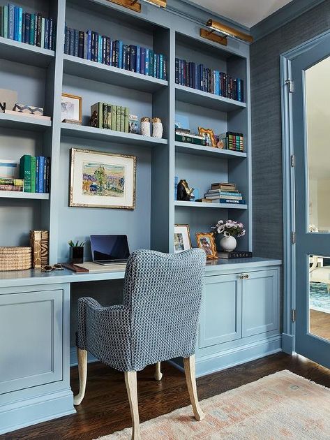 A blue desk chair sits at a blue built-in desk fixed beneath blue built-in bookshelves lit by antique brass picture lights. Blue Built Ins, Garage Remodel Ideas, Remodel Garage, Built In Desk And Shelves, Blue Bookshelves, Studio In Casa, Den Library, Built In Bookshelves, Bookshelf Lighting