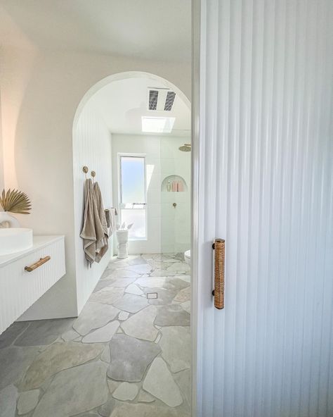 This bathroom was in urgent need of the coastal ensuite makeover and that's what it got. In this renovated bathroom, we see a gorgeous white scalloped door with wicker handles blocking the coastal bathroom. With other features like the stone pave flooring, scalloped vanity, white walls and arch highlighted, you can really enjoy this day spa style bathroom! To see this renovated bathroom in one of our real Australian home tours, click on the pin or go to StyleCurator.com.au. Ensuite Makeover, Stone Floor Bathroom, Stone Tile Bathroom, Coastal Bathroom Design, Spa Style Bathroom, Crazy Paving, Latest Bathroom, Stone Bathroom, Coastal Bathrooms