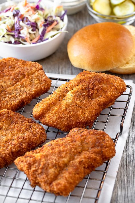 Crispy fish fillets are the star ingredient in this delicious fish sandwich piled high with a tangy and spicy slaw for kick, plus briny pickle slices! | thecozyapron.com #fishsandwich #fishsandwichrecipes #fishsandwichsauce #fishsandwichrecipesfried #fishsandwichrecipessauces Fish Burgers Recipe, Fish Burger Ideas, Breaded Fish Fillet, Fried Fish Fillet, Fish Fillets, Crispy Fish Sandwich, Fish Sandwiches, Cod Fish Sandwich Recipes, Fried Fish Sandwich