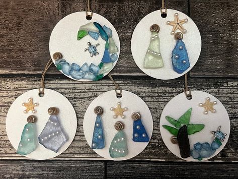 Round wood circles are painted white and a sparkle top coat is added before adding a holiday/coastal scene using sea glass, crushed glass, shells, flat back petals, starfish, small jewelry findings or pebbles. A piece of hemp twine is added for hanging. Each ornament is truly unique. Order any 2 for 27.99 and save!  If you have a request please message me. Choose the number on the ornaments in the photos to receive the specific ornament pictured. if you are ordering 2 for 27.99 please message me the numbers at checkout. These will make a great addition to your coastal tree, or a  special gift for a beach lover. Sea Glass Ornaments Christmas, Beach Glass Ornaments, Sea Glass Ornaments Diy, Sea Glass Christmas Tree Diy, Shell Ornaments Diy, Sea Glass Christmas Ornaments, Sea Glass Ornaments, Shell Christmas Ornaments, Coastal Tree