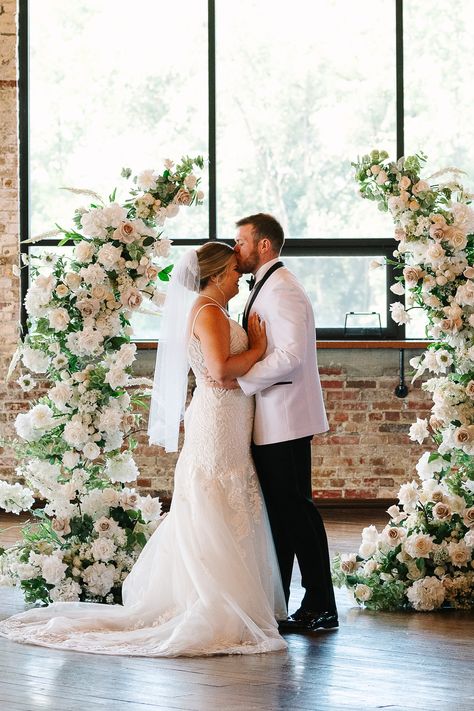 This wedding ceremony at the Biltwell Event Center included a symmetrical open arch finished with with and blush pink florals. The elegant floral wedding ceremony arch was a beautiful contrast against the industrial walls of the Biltwell Event Center. Save this photo to your wedding planning board as inspiration for your wedding ceremony arch. Floral Arch For Wedding Ceremony, All White Arch Wedding, Wedding Half Arch Flowers, White And Pink Wedding Arch, Wedding Half Arch, Deconstructed Wedding Arch, Deconstructed Arch Wedding, Open Arch Wedding, Half Arch Wedding