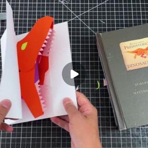 Matthew Christian Reinhart on Instagram: "Welcome to pop-up class, students! May is Dinosaur Month for us here on my channel, so I thought I'd share with you how I made one of my most iconic dinosaur pops from my NYTimes best-selling book 'Encyclopedia Prehistorica - Dinosaurs' - the chomping Tyrannosaurus Rex. Let's go through each step together and build a big biting pop-up carnosaur from scratch!

Learn to make your own:
https://youtu.be/qiTAdmeOkCo?si=QYb3deUzmCDMhOpF" Pop Up Dinosaur Card, Dinosaur Cards, Pop Up Book, Tyrannosaurus Rex, Selling Books, Diy Cards, Ny Times, Dinosaurs, From Scratch