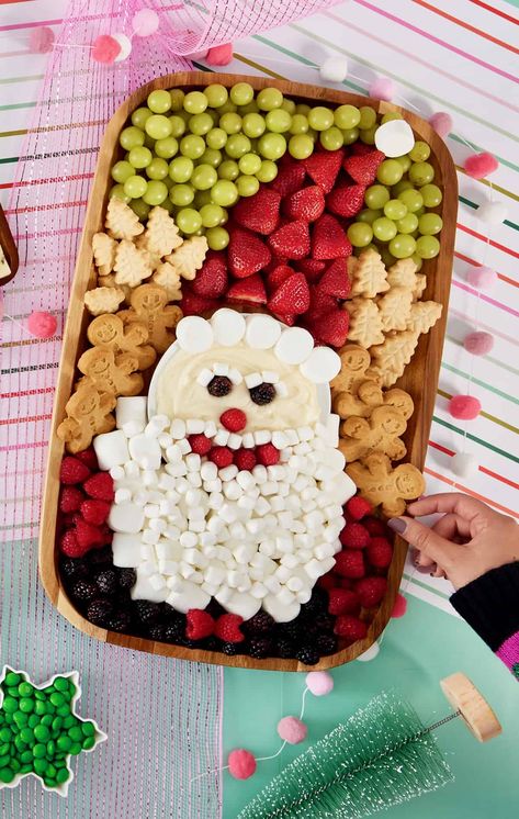 A wood food board decorated with fruit and cookies and marshmallows to look like Santa. Easy Christmas Fruit Tray, Kids Christmas Fruit Platter Ideas, Cute Christmas Fruit Trays, Christmas Tree Fruit Board, Santa Dessert Board, Santa Fruit Platter, Christmas Dessert Fruit, Fruit Tray Ideas Christmas, Christmas Fruit And Veggie Tray Ideas