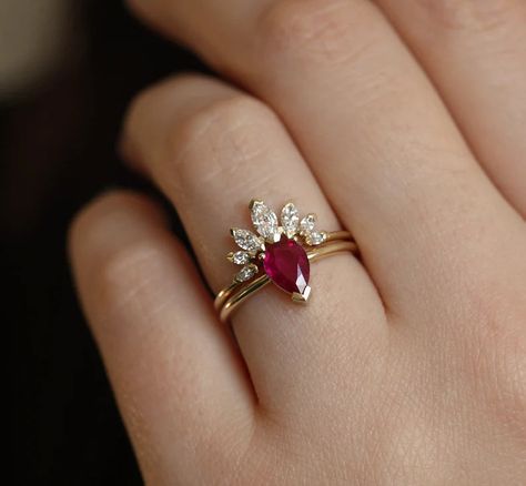 A stunning ring set consisting of a solitaire ruby engagement ring and a marquise moissanite band. This is adjustable and can be personalized. Details:Main gemstone: Genuine RubyShape: Pear Measurements: 0.75 - 0.80 carat (Approximately)Band measurements: 1.6mm (Approximately)Material: 18k Yellow Gold, White Gold, Rose Gold, Platinum (additional fee)Sizes available: 3-8 (Larger and smaller sizes are available as well. Priced upon request.) Ruby Engagement Ring Set, Diamond Crown Ring, Ruby Wedding Rings, Ruby Wedding, Diamond Crown, Gold Ring Designs, Ruby Engagement Ring, Crown Ring, Rose Gold Engagement