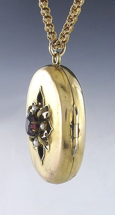 Presented is a fabulous 14 karat gold Victorian American locket pendant with  chain. This piece dates to around the 1870s. The locket is oval form with a  stylized flower on the front. The center of the 'flower' is an oval faceted  garnet, which is a rich red-pink stone. Surrounding the garnet are four real  seed pearls. The interior of the locket has the original bezel and glass on each  side, perfect for a photo, a lock of hair, or other memento. There is enough  space behind the glass for fol Pearl Locket, Lock Of Hair, Purple Gems, Pendant With Chain, Jewel Box, Pink Stone, Red Gold, Locket, Garnet