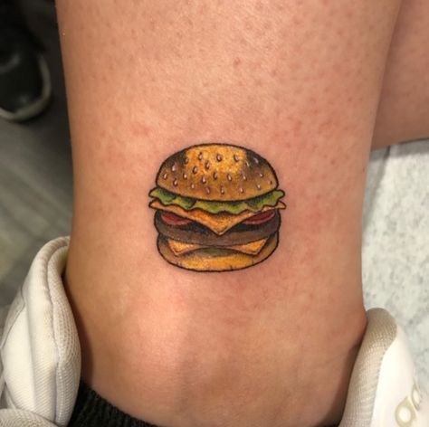 This is a fast-food tattoo of a burger. If you enjoy eating burgers, you should show your affection for them by getting a burger design tattooed on your body. This bright burger tattoo adds a realistic and feminine touch to... Sandwich Tattoo, Burger Tattoo, Food Tattoos, Tattoo Color, Ankle Tattoo, Couple Tattoos, Infinity Tattoo, Cheeseburger, Jesus Fish Tattoo