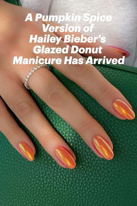 Orange almond-shaped nails holding a green purse Orange Glazed Donut Nails, Hailey Bieber Orange Nails, Burnt Orange Glazed Nails, Glazed Donut Nails Orange, Orange Hailey Bieber Nails, Orange Irridescent Nails, Glazed Orange Nails, Iridescent Orange Nails, Fall Iridescent Nails