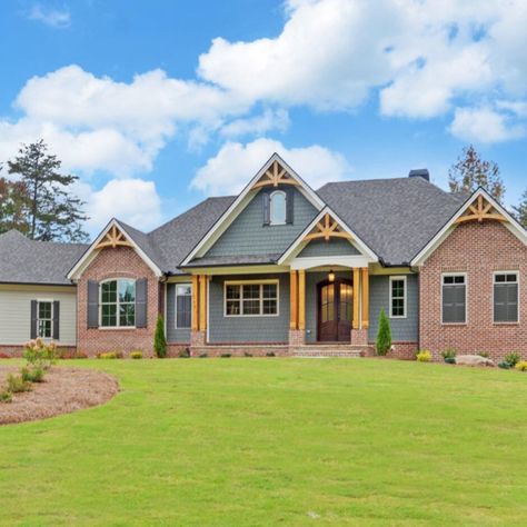 The residence, featuring a three-car garage, boasts a spacious front porch adorned with stone flooring. Inside, the family room showcases a soaring vaulted ceiling and a floor-to-ceiling stone fireplace, flanked by custom wood grain cabinets and bookshelves. Brick House With Shaker Siding, Brick And Hardy Plank Exterior, Cedar Shake Siding Accent With Brick, Gable End Brick Detail, Cobblestone Hardie Plank Siding, Cedar Gable, Gainesville Georgia, Hardie Board, Board And Batten Shutters