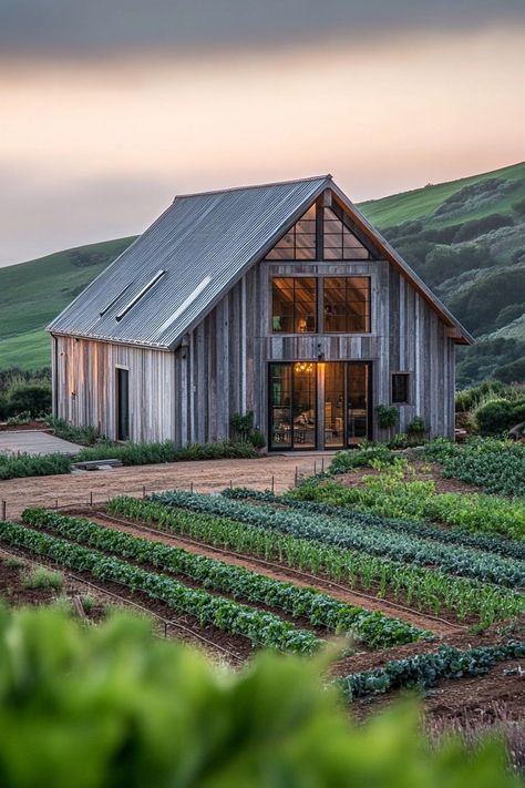 Modern barn style house facade with reclaimed wood accents on a farm with veggie gardens green hills in the background. Check out all of these creative and charming barn-style houses, blending rustic charm with modern functionality. These will change they way you look at barns completely. Old Barn Restoration, Educational Farm, Stone House Revival, Ranch Landscape, Rustic Barn Homes, Small Barn Home, Barn Exterior, Pole Barn House, Modern Barn Style