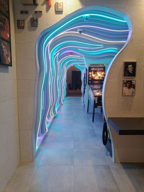 Retro cut wavy hallway cut hole in the wall with neon lights  with back to the 80's theme serving pizza and dont forget to take it back with the many 80s arcade games! Arcade Cafe Interior Design, 80s Themed Restaurant, Futuristic Arcade, Arcade Restaurant, Arcade Interior, Arcade Ideas, Modern Arcade, Game Center, Arcade Design