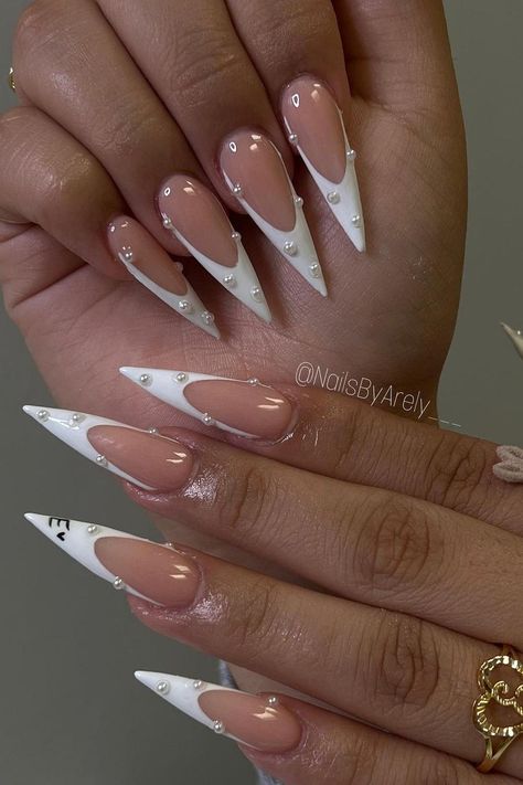 These stiletto nails feature a chic duo of natural pink bases transitioning into glossy white tips, creating a sophisticated French manicure effect. The addition of small white pearls carefully placed along the smile lines enhances the elegance. One nail stands out with a minimalist face design, giving a playful twist to the otherwise classic look. Perfect for those who appreciate a touch of fun within a polished style.  // Photo Credit: Instagram @nailsbyarely___ Trendy Stiletto Nails, Stiletto Nails Ideas, French Stiletto Nails, White Stiletto Nails, Acrylic Nails Stiletto, Stilleto Nails Designs, Long Stiletto Nails, Long Stiletto, Fancy Nails Designs