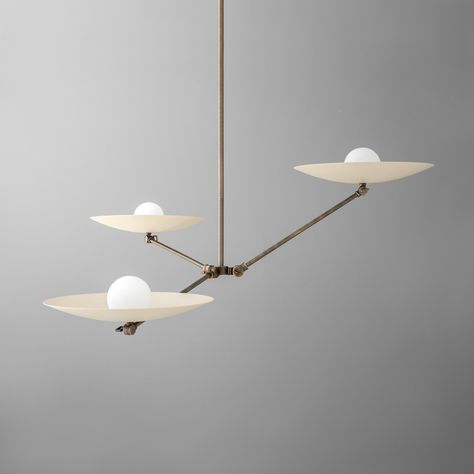 Elevate your home with this artistic and modern three-light chandelier, featuring an innovative design with wide, disc-like shades and a sleek antique brass finish. The asymmetrical arms create a dynamic visual effect, while the frosted glass globes provide soft, ambient lighting. Perfect for contemporary dining rooms, living spaces, or kitchen islands, this chandelier blends form and function to make a bold statement. Its unique structure and minimalist aesthetic make it an ideal choice for those seeking to add a touch of modern sophistication to their interior decor. FINISH -------------------- *Antique Brass - Made of solid brass that has been aged and lacquer sealed *Raw Brass -  features solid unfinished brass that is hand cleaned before leaving our shop. The brass will age and patina Modern Living Room Lights, Unique Chandelier, Antique Brass Lighting, Dining Room Contemporary, High End Lighting, Glass Globes, Traditional Lighting, Contemporary Dining, Brass Lighting