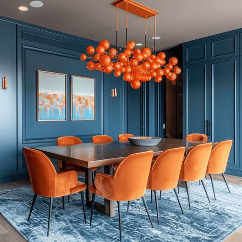 A modern dining room with a complementary color scheme of blue and orange, featuring blue walls and an orange statement chandelier Blue Dinning Room, Rachael Riley, Red Velvet Chair, Modern Table Decor, Teal Interiors, Blue Interior Design, Autumn Interior, Interior Color Schemes, Interior Design Guide