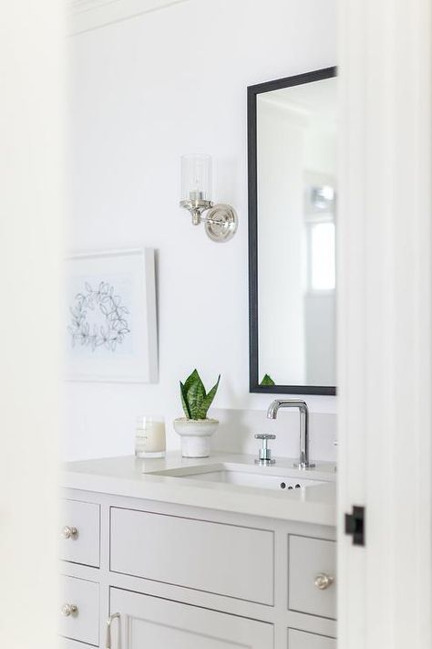 A light gray bath vanity adorned with chrome hardware is topped with an off-white quartz countertop holding a chrome faucet kit beneath a black vanity mirror lit by chrome and clear glass sconces. Black And Chrome Bathroom, Black Vanity Mirror, Inset Drawers, Brick Bathroom, Chrome Bathroom Hardware, Top Bathroom Design, Quartz Backsplash, Bathroom Faucets Chrome, Black Faucet