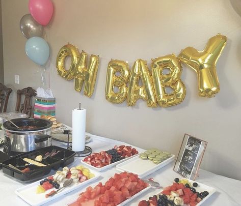 Oh Baby balloons. Simple gender reveal party. Appetizer table with macaroons. fruits, sandwiches, cheese, and crackers. Finger foods with framed sonogram. Pink, blue, and silver themed decorations. Gender Reveal Dinner Restaurant, Gender Reveal Ideas Pink And Blue, Pink Blue White Gold Gender Reveal, Pink And Blue Deviled Eggs Gender Reveal, Pink And Blue Food Gender Reveal, Simple Gender Reveal, Appetizers Table, Baby Balloon, Reveal Parties