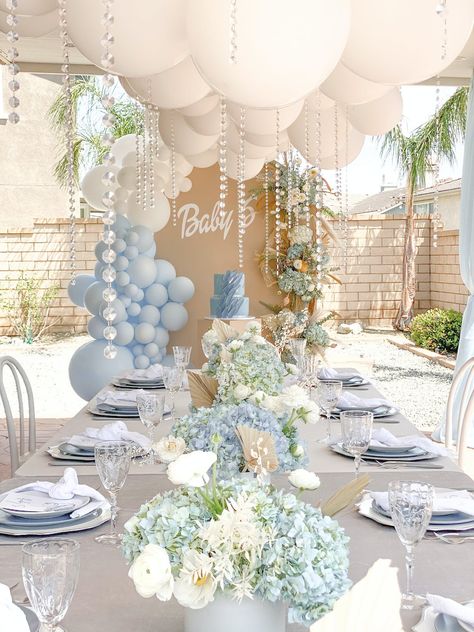 Event Du Jour flawlessly executed this blue and white baby shower. Pearl details cascaded from the balloon arrangement suspended above the table topped with arrangements of blue hydrangeas and white peonies. Unique charger plates and textured glassware furthered the picture-perfect tablescape. Bapstim Decorations, Boys Christening Ideas, Neutral Blue Baby Shower Ideas, April Boy Baby Shower Ideas, Spring Boy Baby Shower Themes, Luxury Baby Shower Ideas Boy, Outdoor Babyshowers, Classy Boy Baby Shower Ideas, Bris Decor