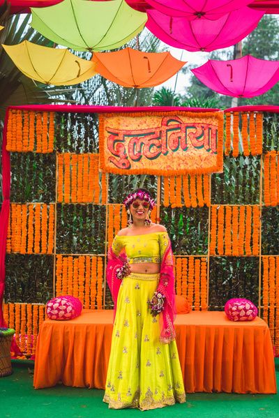 Mehendi Decor - Marigold Decor with Hanging Umberellas | WedMeGood | Bride in a Yellow and Pink Lehenga with Orange and Pink Decor  #wedmegood #indianbride #indianwedding #bridalmehendi #mehendidecor #mehendioutfit #marigolddecor #orange #pink Indian Wedding Deco, Haldi Ceremony Decorations, Indian Wedding Theme, Mehendi Decor Ideas, Desi Wedding Decor, Marriage Decoration, Mehndi Decor, Wedding Mandap, Wedding Design Decoration