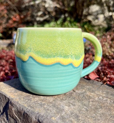 "Welcome to Kingfisher Potters!  This beautiful light wheel-thrown stoneware mug is glazed using turquoise and yellow glazes.  The blue drip glaze gives each mug an individuality while also being a member of a beautiful set.  Both glazes are food safe and microwave safe.   Due to the nature of the yellow drip glaze the image represents the style and color of the piece. The exact item shipped to you will vary slightly in pattern markings. The process for making these mugs is multi-stepped and individualized.  First the form of the mug is thrown using a stoneware clay on the wheel.  The handle is pulled separately and then attached.  The piece once all the parts are formed is left to dry and then bisque fired.  The bisque fired pots are dipped in the turquoise glaze and left to dry.  Finally Glaze Ideas For Pottery, Pottery Glaze Ideas Color Combos, Ceramic Glaze Ideas, Glazed Mugs, Ceramic Handles, Glazing Ideas, Yellow Mug, Blue Drip, Fire Pots