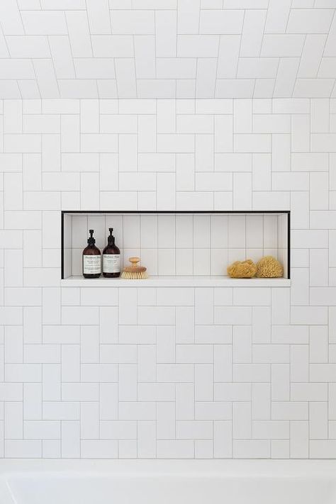 White geometric wall tiles in a drop in bathtub boasting a black-framed tiled horizontal shower niche with white interior tiles. Herringbone Tile Bathroom, Tile Shower Niche, White Herringbone Tile, Bathtub Cover, Bathtub Wall, Bathroom Niche, Scandinavian Farmhouse, Gray Shower Curtains, Bathtub Tile