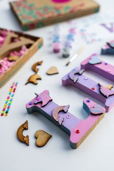 This kids personalised unicorn wooden name kit is sure to be a hit with little crafters!The perfect birthday gift, party craft or Christmas gift! Each kit includes:
* Wooden letters in the name of your choice (select number of letters and enter name in personalisation section)
* a selection of paints
* wooden paint brush
* wooden unicorn, rainbow and heart charms
* gem stickers
* Kraft box with personalised label 
The number of paint pots and and wooden charms varies according to the number of letters in the name. Decorate your child’s room with the name once completed!The letters and charms are made from wood. The letters are 10cm high and can stand unsupported.
Note: this kit contains small components, which may represent a choking hazard, and are not suitable for children aged 3 and und