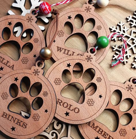 Your custom name of choice beautifully engraved on a laser cut Paw Print Christmas Bauble made from Beech Wood. A lovely handcrafted Christmas Dog decoration that adds warmth and love to Christmas as a Personalised keepsake. A versatile design that can be hung on a Christmas tree, added as a Christmas gift, or used as a lovely addition to a Christmas gift package.  Approx Size: 100 x 85mm  Please note these are natural wood so each piece will be unique! Paw Print Christmas, Christmas Dog Decor, Diy Laser Engraver, Engraved Christmas Ornaments, Christmas Gift Packaging, Christmas Gifts For Pets, Fall Arts And Crafts, Laser Cut Wood Crafts, Laser Engraved Gifts