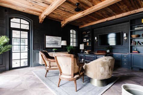 In the office, a wall-mounted TV screen all but disappears against near-black grasscloth wallpaper. Intricately laid wood flooring and a ceiling clad in reclaimed oak adds warmth and contrast to the room’s dark walls, painted with Sherwin-Williams‘ Iron Ore. Photo by Rebekah Westover. Moody Office Design, Moody Office, Utah Style, Cle Tile, Walnut Floors, Industrial Floor Lamps, Wood Ceiling, Modern Office Chair, Industrial Flooring